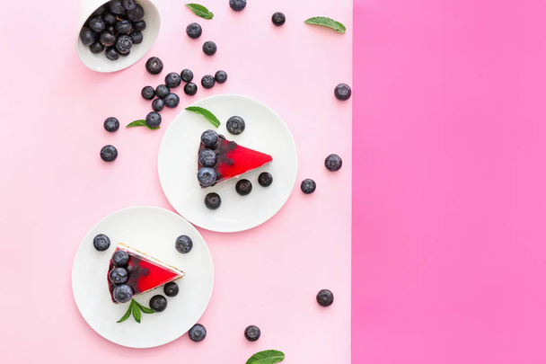 Pieces of tasty blueberry cheesecake on color background - Foto, afbeelding