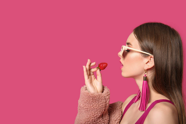 Fashionable young woman with strawberry on color background - Fotoğraf, Görsel