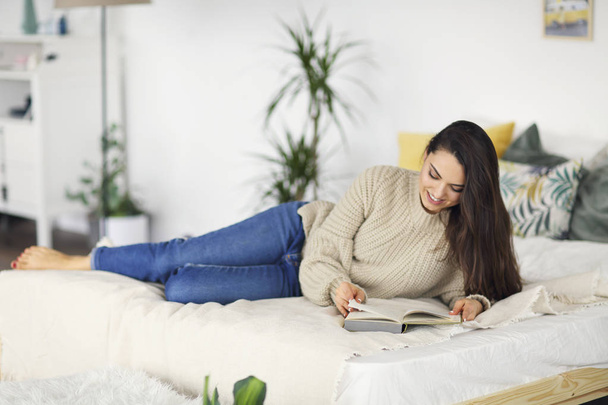 Young happy brunette woman with book wearing sweater  - Foto, Imagen