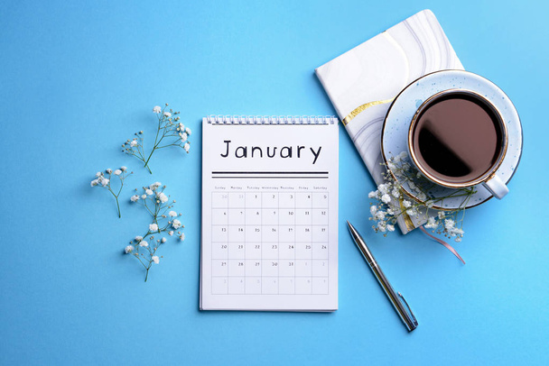 Flip paper calendar, cup of coffee and notebook on color background - Φωτογραφία, εικόνα