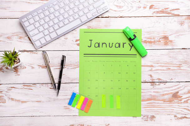 Paper calendar, PC keyboard and stationery on light wooden background - Photo, Image