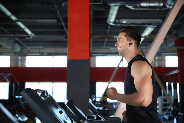 Sporty young man training on treadmill in gym - Photo, Image