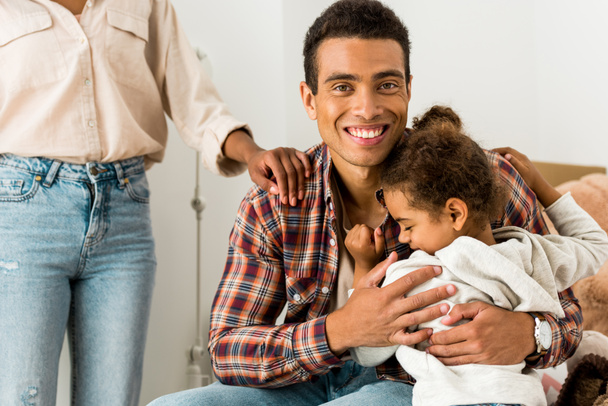 cropped view of woman standing near african american man while father hugging kid  - Фото, изображение