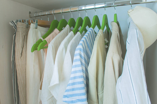 summer wardrobe with linnen clothes on green hangers - 写真・画像
