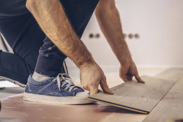 Working with hands installs a laminate board, professional flooring installation - 写真・画像
