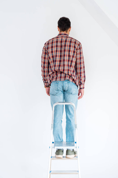 pohled na člověka stojícího na žebříku a pohled na zeď izolovanou na bílém - Fotografie, Obrázek