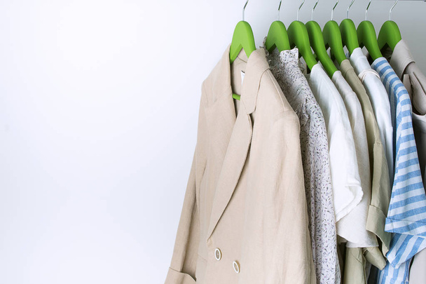 летний гардероб с льняной одеждой на зеленых вешалках
 - Фото, изображение