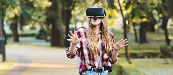 panoramatický záběr překvapena mladá dívka v příležitostných šatech s využitím sluchátek VR - Fotografie, Obrázek