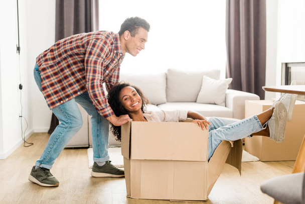 full length view of african american husband trying to move box with wife  - Photo, Image