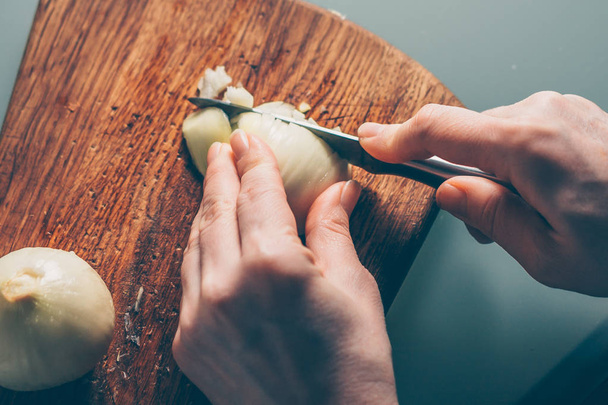 The cook cuts the onion on a cutting board - Foto, imagen