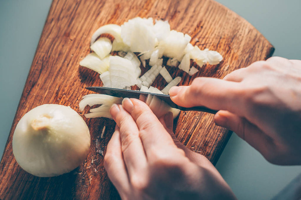 The cook cuts the onion on a cutting board - Foto, imagen
