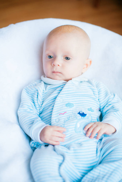 Αξιολάτρευτο μωρό αγόρι σε λευκό ηλιόλουστη κρεβατοκάμαρα. Νεογέννητο παιδί ξεκούραστη στο κρεβάτι. Φυτώριο για μικρά παιδιά. Κλωστοϋφαντουργίας και της κρεβάτια για τα παιδιά. Οικογένεια το πρωί στο σπίτι - Φωτογραφία, εικόνα