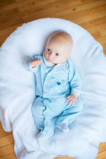 Adorable baby boy in white sunny bedroom. Newborn child relaxing in bed. Nursery for young children. Textile and bedding for kids. Family morning at home - Φωτογραφία, εικόνα