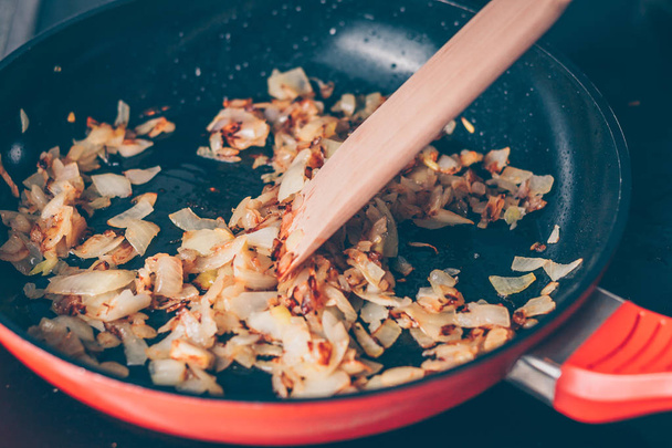 The cook stirs fried onions in a frying pan - Photo, image