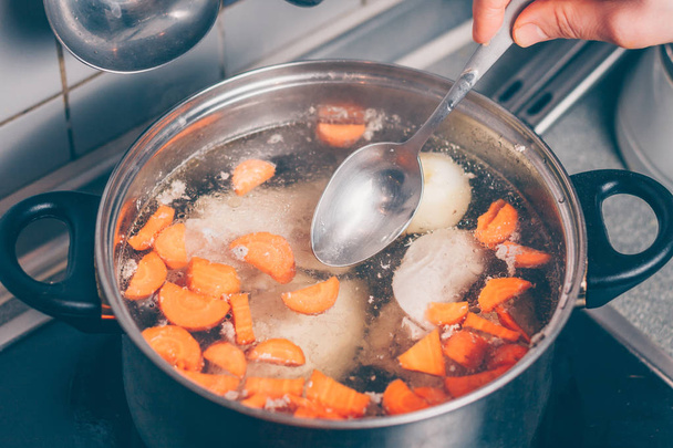 Cook cooks broth in a saucepan on the stove - Foto, imagen