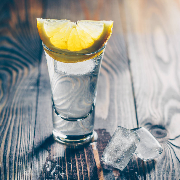 Elegant glass of vodka with a slice of lemon on top - Фото, изображение