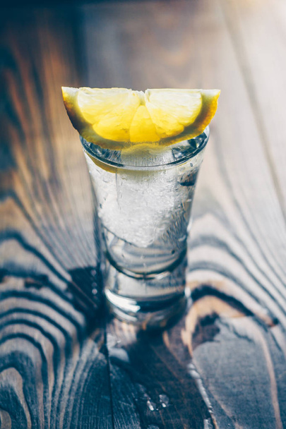 Vertical format, a glass of cold appetizing vodka on the board - Photo, Image
