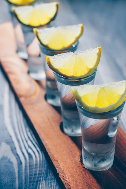 Vertical view of a vodka shot with a lemon at a party - Фото, зображення