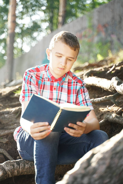 Adolescente menino leitura livro de exercícios sobre a natureza
 - Foto, Imagem