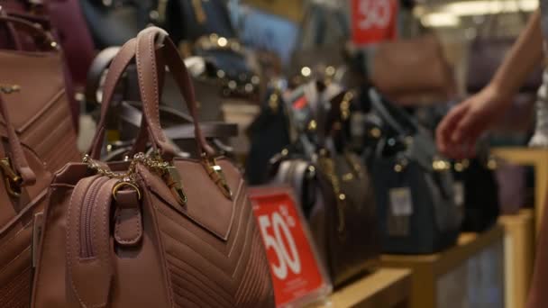 Young Woman Choosing Synthetic Leather Bag in Fashion Clothing and Accessories Shop. Customer Girl Buying Handbag on Sale in Shopping Mall. Discount concept. 4K - Footage, Video