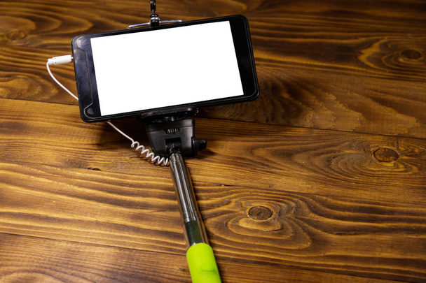 Monopod voor selfie met slimme telefoon op houten bureau - Foto, afbeelding