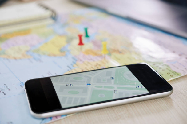 Nahaufnahme eines modernen Smartphones mit GPS-Anwendung, die Stadtplan zeigt  - Foto, Bild