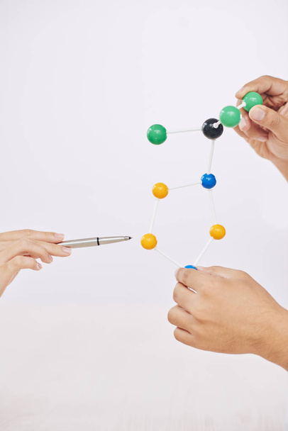 Manos de cultivo de los científicos que sostienen el modelo molecular colorido y que tienen presentación sobre fondo blanco
 - Foto, Imagen