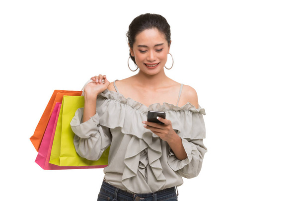 Asian woman carry paper bags and uses smartphone - Photo, Image