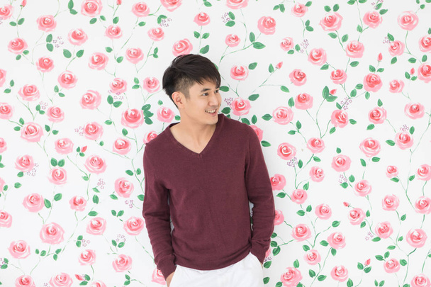 Asiatischer Mann steht und posiert auf floralem Hintergrund - Foto, Bild