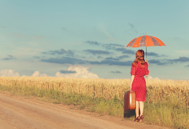 roodharige meisje met paraplu en koffer in buiten - Foto, afbeelding