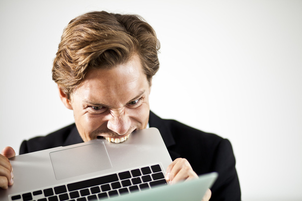 Homem mordendo um laptop em frustração
 - Foto, Imagem