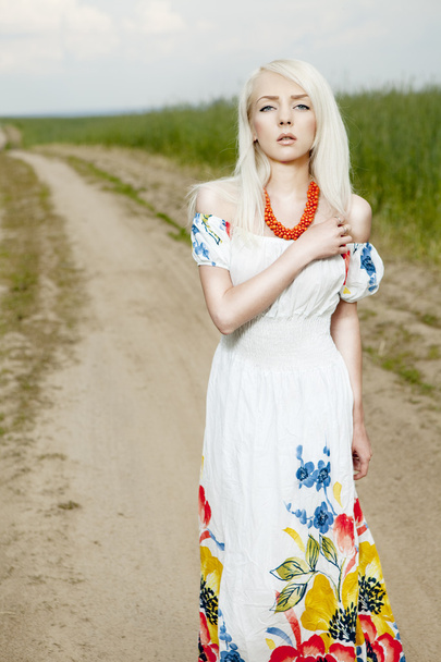 Rural woman standing on the road by the field - Foto, afbeelding