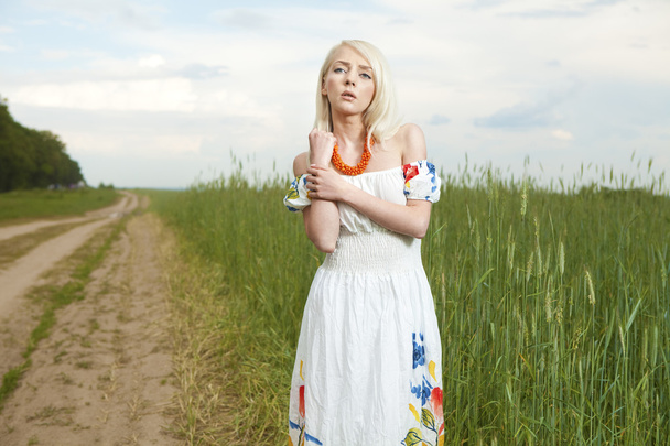 Rural woman standing by the wheat field - Fotoğraf, Görsel