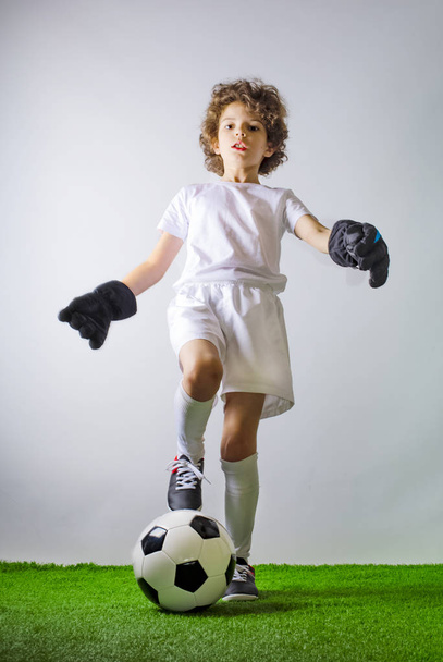 Kid - soccer champion. Boy goalkeeper in football sportswear on stadium with ball. Sport concept. - Zdjęcie, obraz