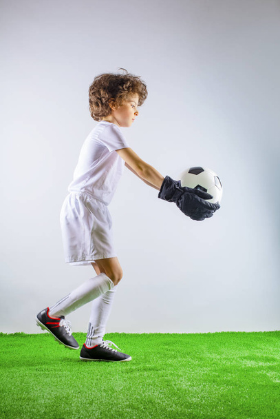 Kid - soccer champion. Boy goalkeeper in football sportswear on stadium with ball. Sport concept. - Photo, Image