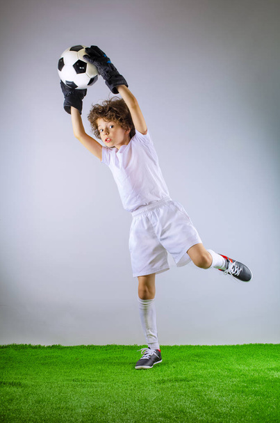 Kid - soccer champion. Boy goalkeeper in football sportswear on stadium with ball. Sport concept. - Foto, imagen