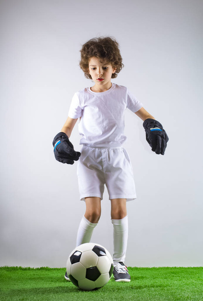 Kid - soccer champion. Boy goalkeeper in football sportswear on stadium with ball. Sport concept. - Foto, immagini