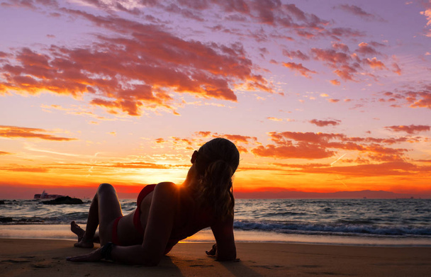 Woman sitting on the beach at sunset  - Valokuva, kuva