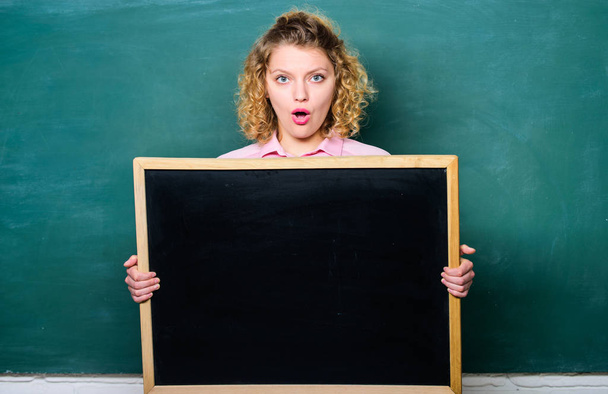 here is your advertisement. informations board. announcement concept. place to write task. surprised student girl hold blank board. woman teacher at blackboard. copy space - Фото, изображение