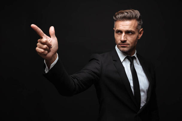Portrait of serious confident businessman dressed in formal suit pointing finger and looking aside - Fotoğraf, Görsel