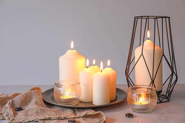 schöne brennende Kerzen auf dem Tisch vor grauem Hintergrund - Foto, Bild