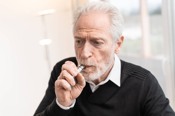 Homme âgé fumant cigarette électronique
 - Photo, image