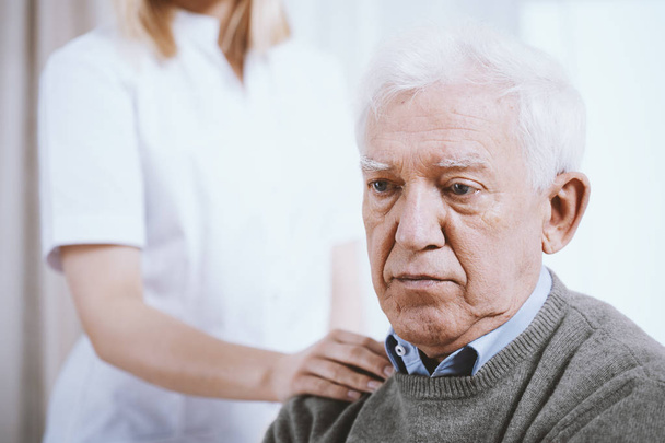 Portrait of senior man with hand of supporting nurse on his shoulder - Photo, Image
