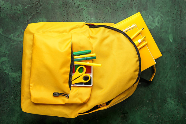School backpack with stationery on color background - Fotó, kép