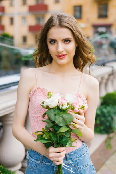 Girl with makeup holding a bouquet of white and pink roses, she stands near the balusters. She is happy and waiting for someone - Photo, image