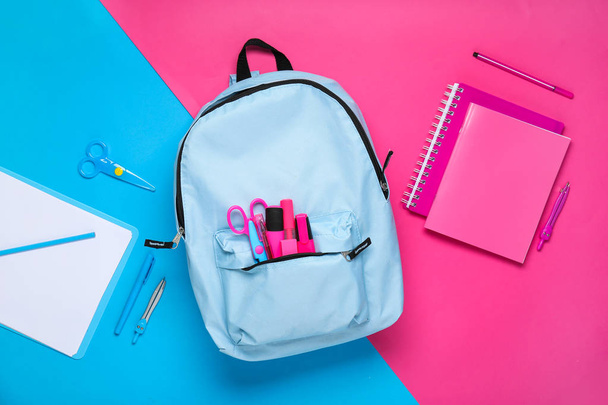 Школьный рюкзак с канцелярскими принадлежностями на фоне цвета - Фото, изображение
