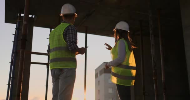 Knappe bouw man en vrouw werknemers in beschermende helmen en vesten schudden handen tijdens het werken in het kantoor centrum. - Video