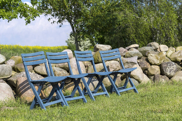 Four blue chairs, standing in a row on the meadow - Photo, Image