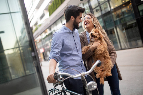 Beautiful young couple walking dogs and bicycles outdoors in city - Foto, Bild