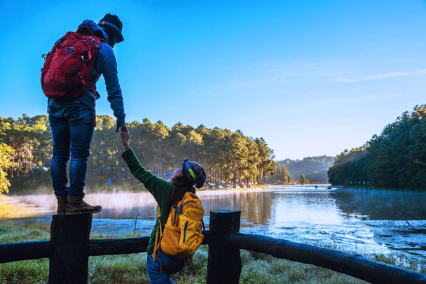 Νεαρό ζευγάρι ευτυχισμένο Απολαμβάνοντας τον τουρισμό της φύσης, βλέποντας την όμορφη λίμνη. - Φωτογραφία, εικόνα